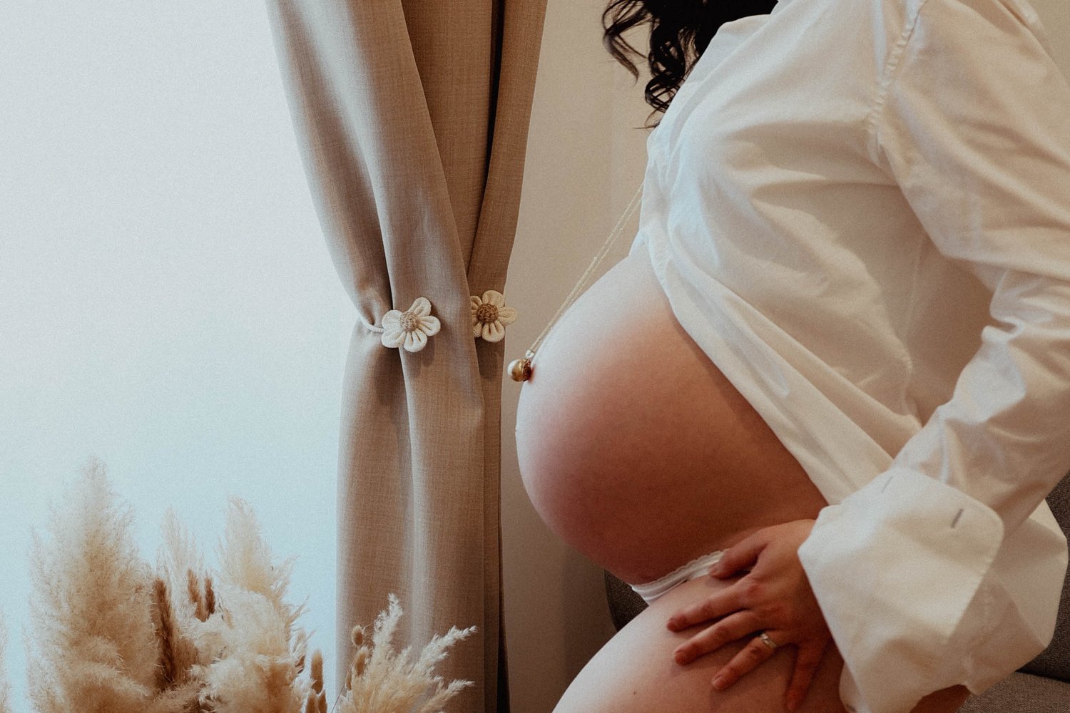 Grossesse — profil du ventre près d'un rideau