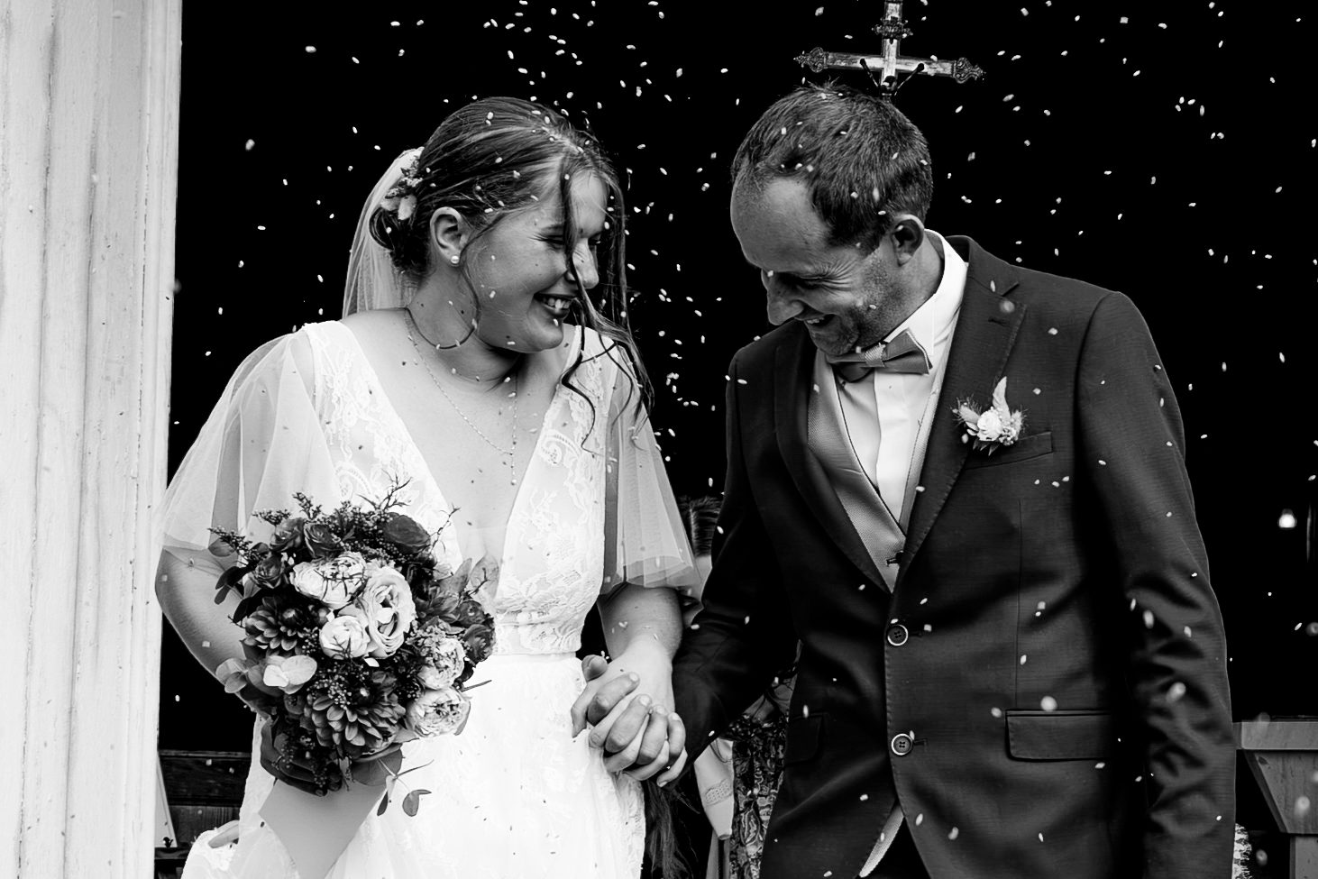 Mariage — les mariés sous une pluie de confettis à la sortie de l'église, noir et blanc