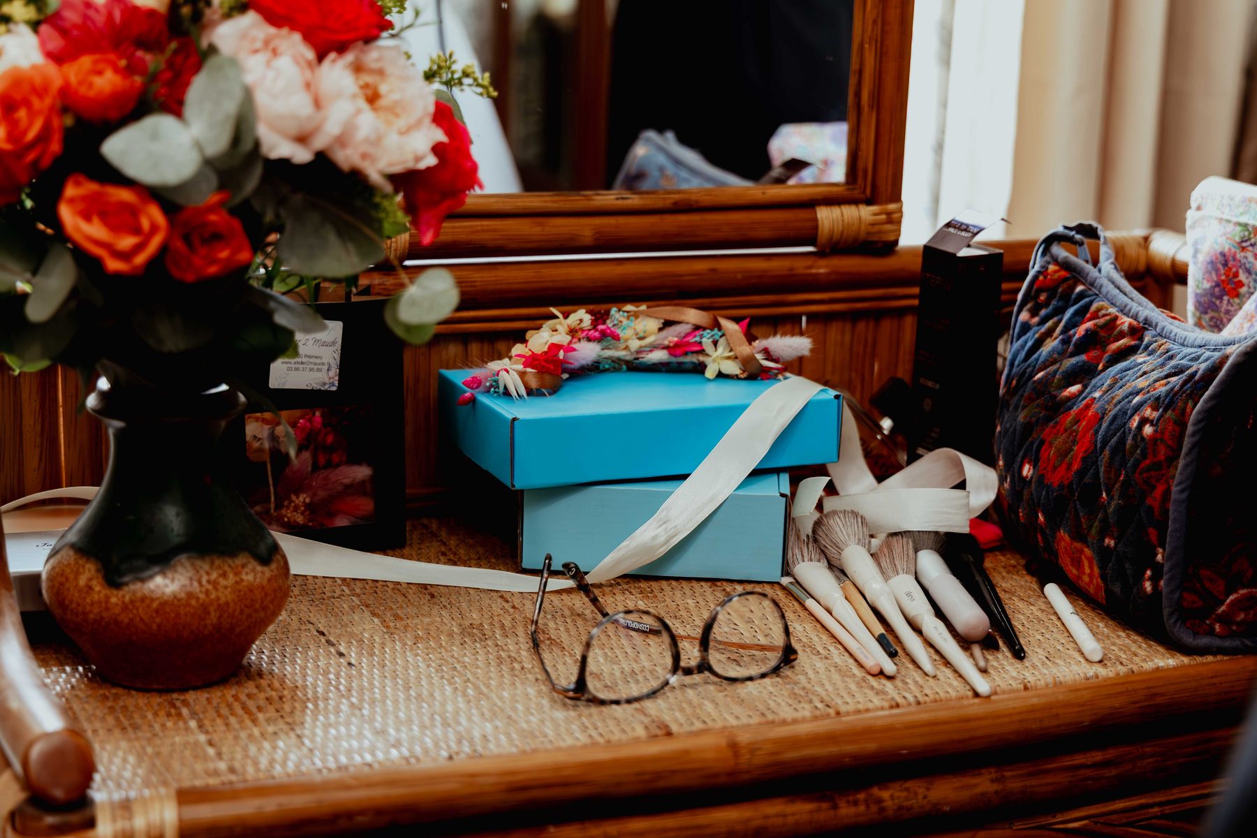 Mariage — coiffeuse avec fleurs, lunettes et pinceaux de maquillage