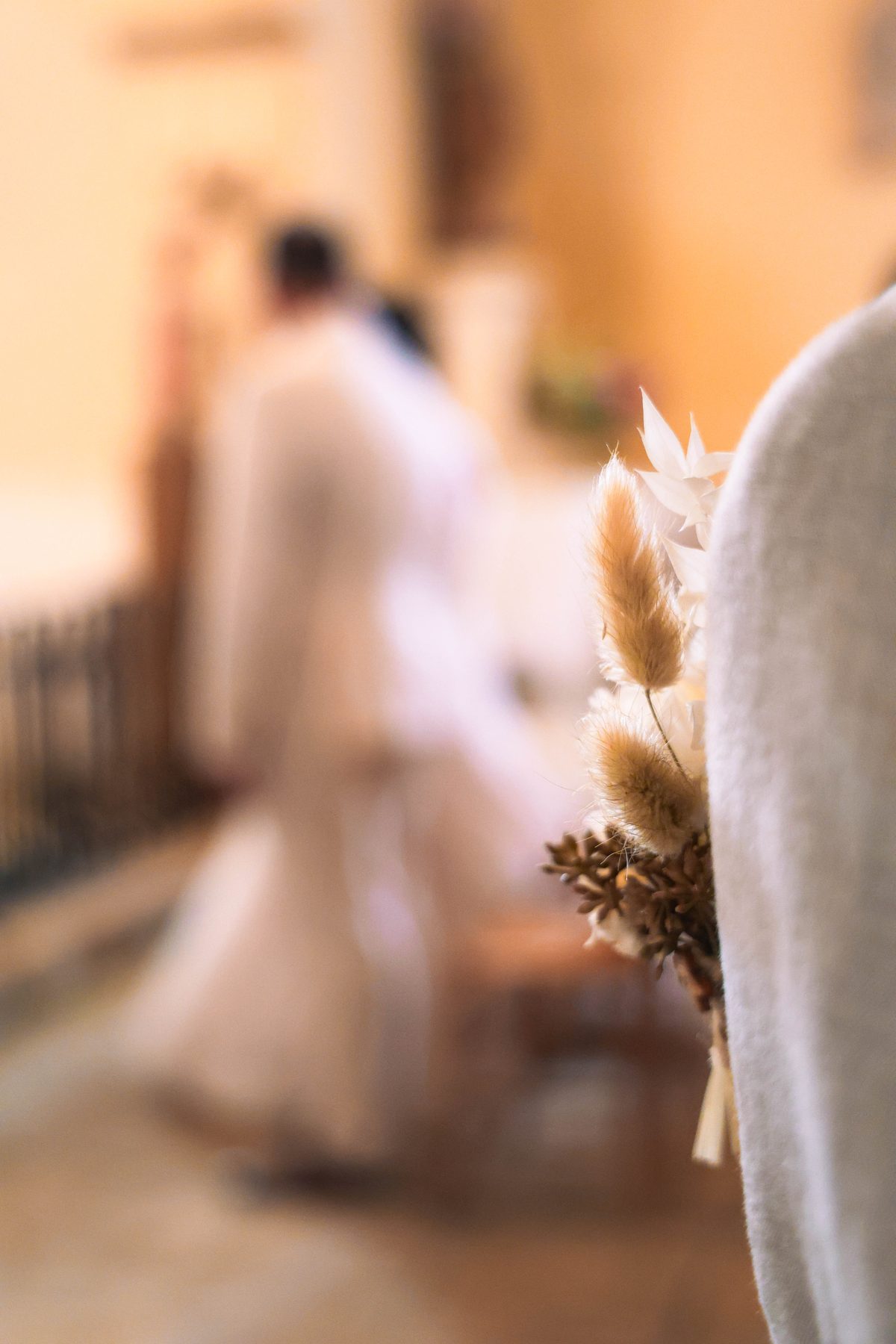 Mariage — bouquet de fleurs séchées au premier plan, mariés en arrière-plan