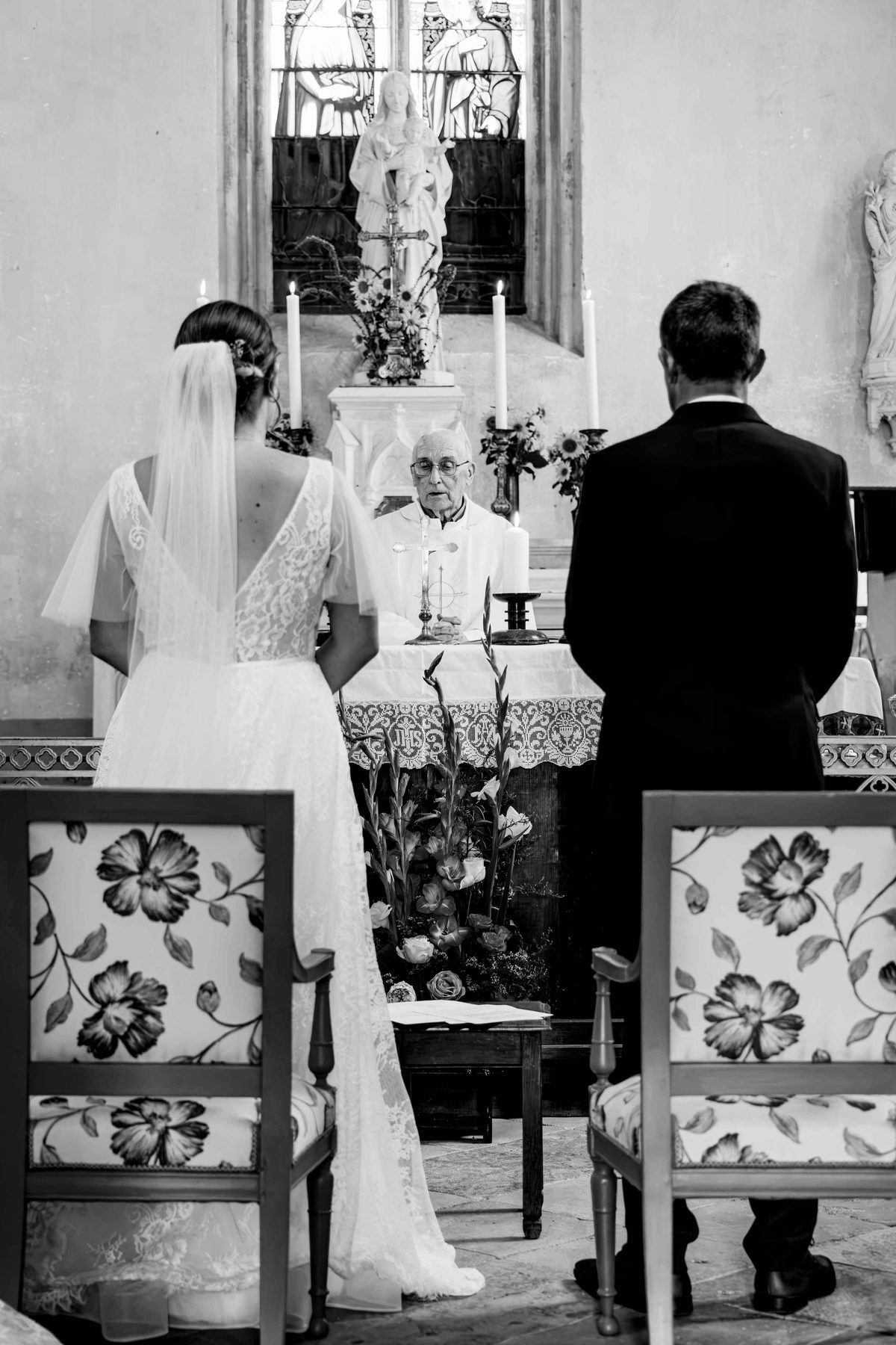 Mariage — les mariés face au prêtre pendant la cérémonie, noir et blanc